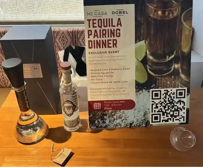 The Tequila Pairing Dinner flyer on a Mi Casa table beside bottles of Maestro Dobel tequila