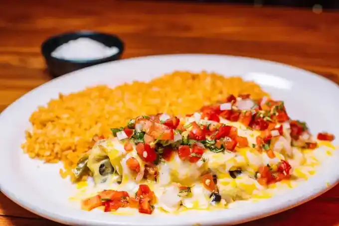 An enchilada plate with rice and pico de gallo
