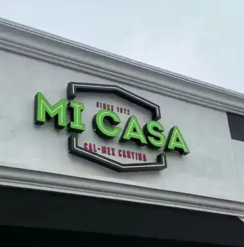 The green three-dimensional Mi Casa Cal-Mex Cantina sign on a grey wall